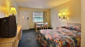 A hotel room with a bed, a desk with a computer, a chair, a window with curtains, and a door. - 1 Queen Bed | Micfridge, Non-Smoking (Seattle)
