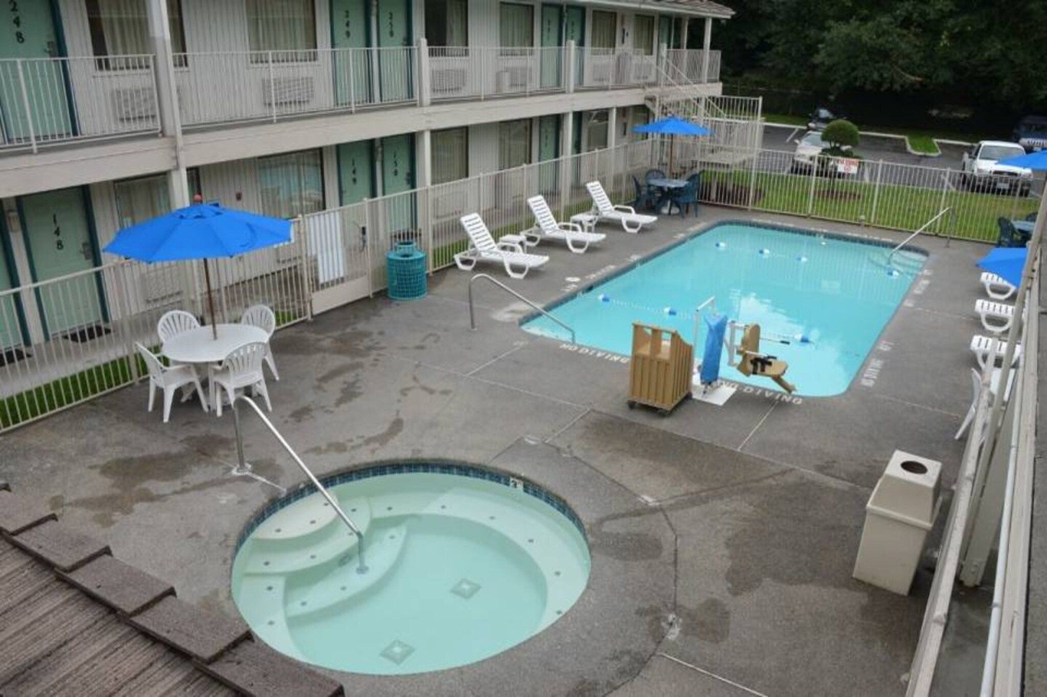 A hotel pool area with a hot tub, lounge chairs, and umbrellas.