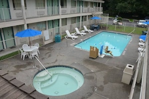 Zona de piscina hotelera con un jacuzzi, sillones de descanso y sombrillas.