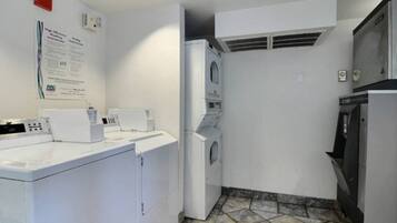 A laundry room with a washing machine, dryer, and stacked laundry baskets.