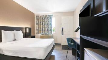 Une chambre d’hôtel avec un lit, un bureau, une chaise, une télévision et une porte.