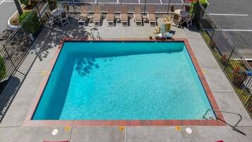 Une piscine rectangulaire dont le bord est recouvert de carrelage, et qui est entourée d’une clôture en métal.