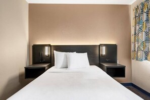 Habitación de hotel con una cama grande, dos mesitas de noche y un cabecero con iluminación integrada.