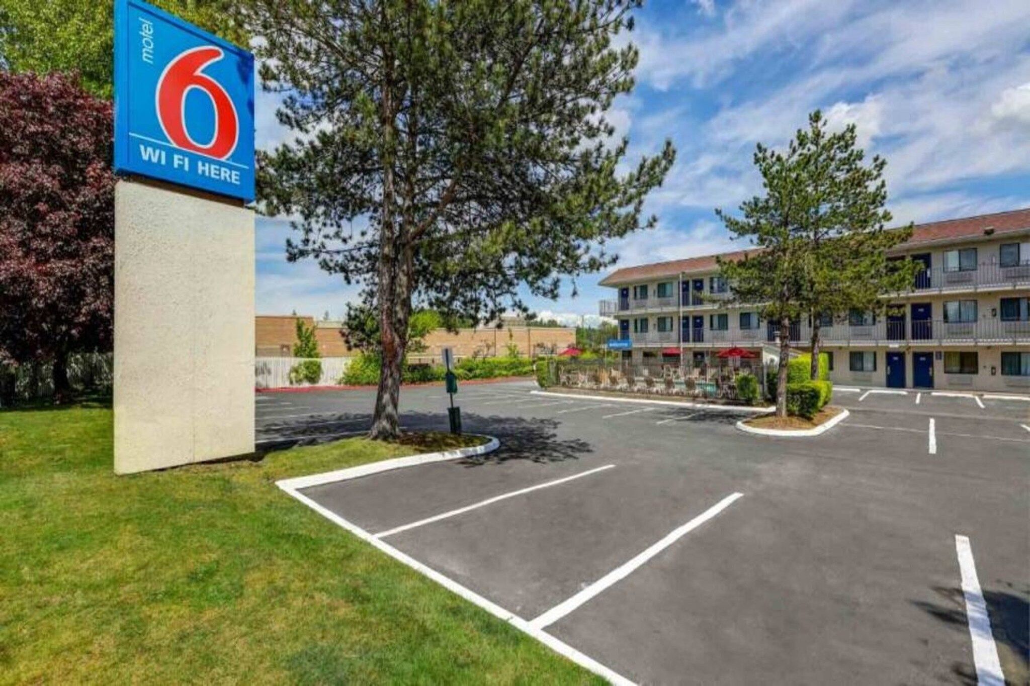 A motel with a large parking lot, a sign indicating WiFi availability, and a building with multiple floors and balconies.