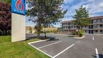 A motel with a large parking lot, a sign indicating WiFi availability, and a building with multiple floors and balconies.