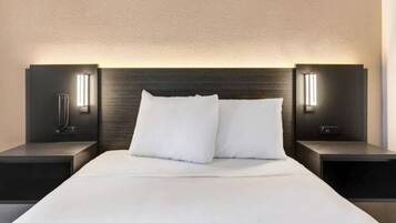 Une chambre d’hôtel moderne avec un grand lit, deux tables de chevet et des lampes de lecture fixées au mur.
