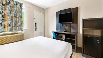 Une chambre d’hôtel équipée d’un lit, d’un bureau avec un ordinateur, d’une télévision et d’un mini-bar.