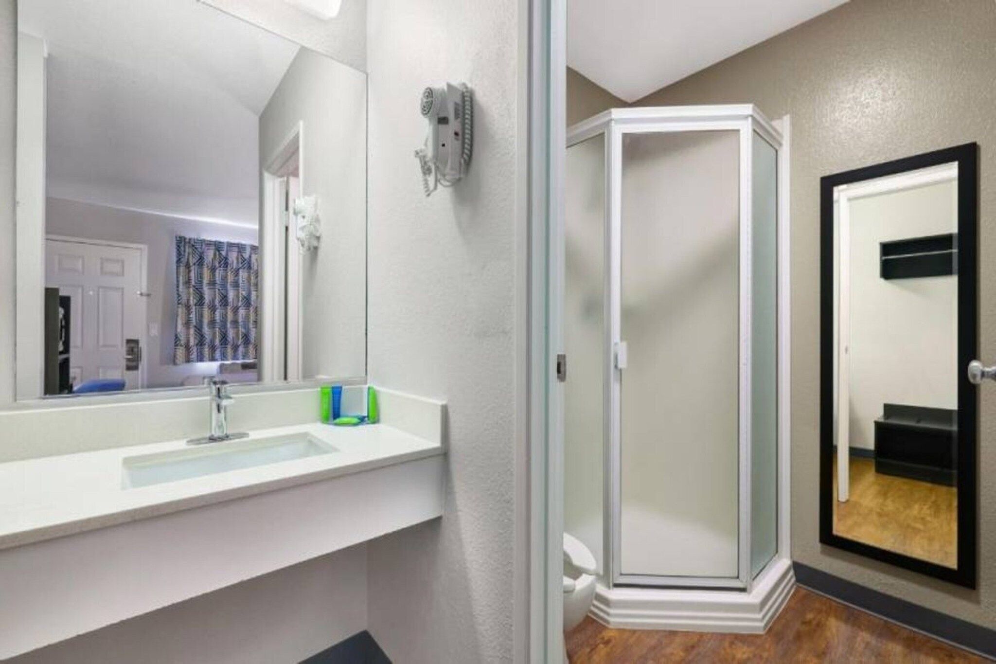 A modern bathroom with a white vanity, a glass shower enclosure, and a door leading to another room.