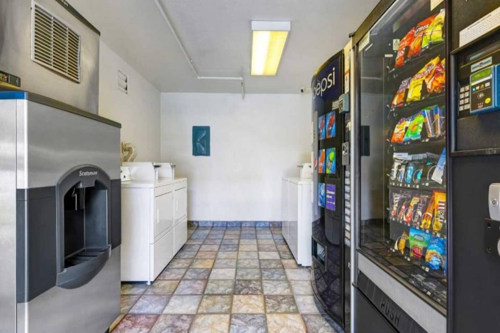 Un espace en libre-service comprenant un distributeur automatique, un réfrigérateur et un lave-linge.