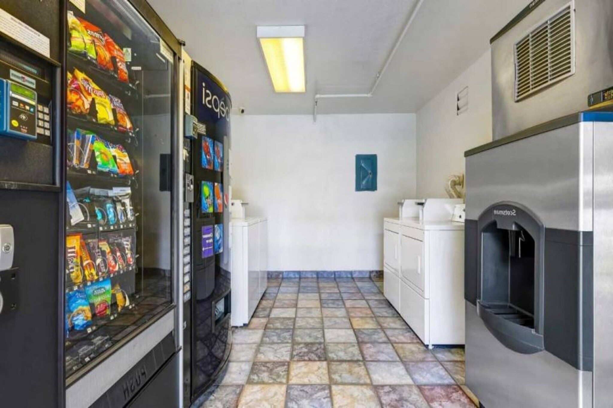 Une petite cuisine équipée d’un four à micro-ondes, d’un réfrigérateur et de distributeurs automatiques.