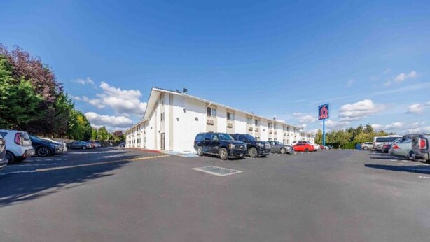 Un motel avec une rangée de chambres, un parking et un ciel dégagé.