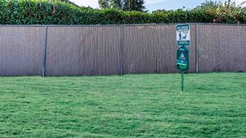 A fenced yard with a pet waste disposal bin and a sign indicating the area is clean.