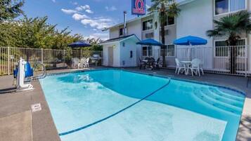 A hotel with a swimming pool, outdoor seating, and a sign indicating the number 6.