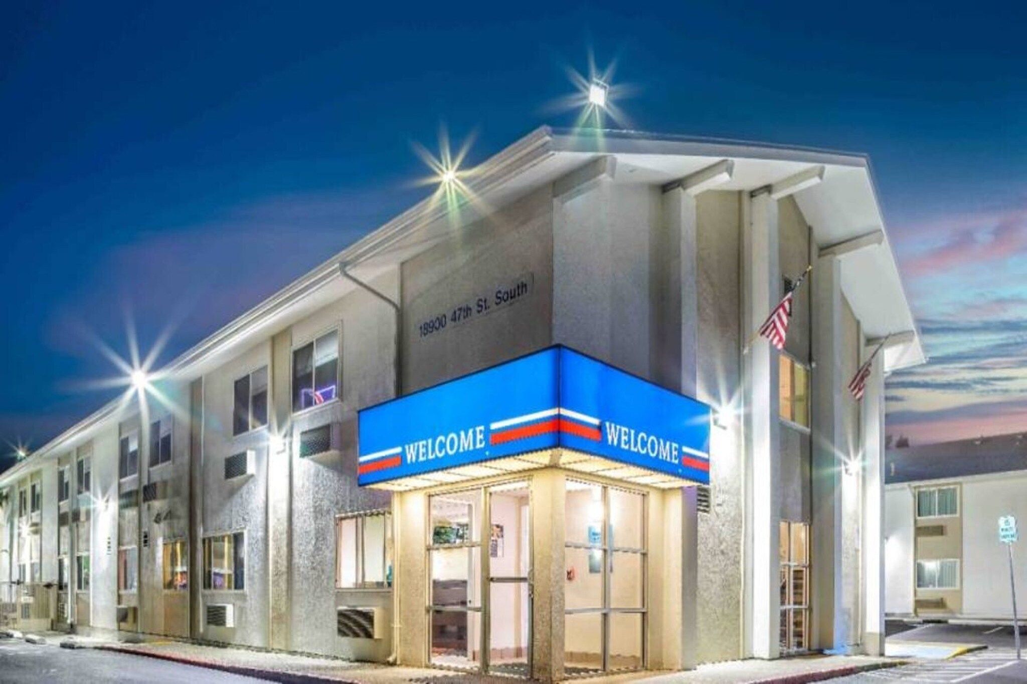A hotel with a 'WELCOME' sign, located at 18900 47th St. South, featuring a modern facade and a clear view of the street.