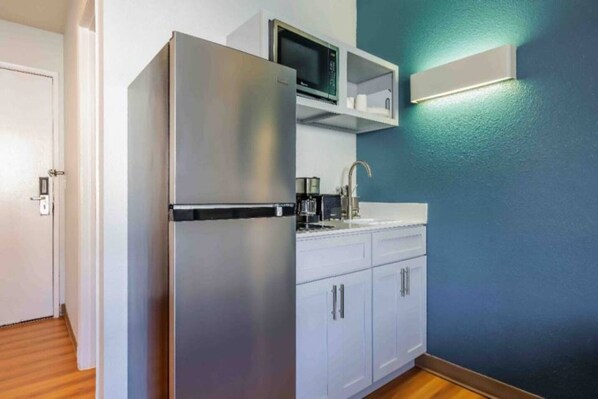 A compact kitchen with a refrigerator, microwave, and a coffee maker.