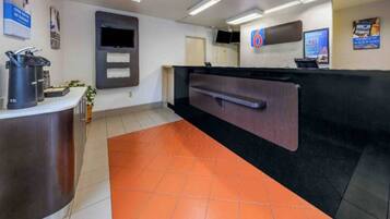 A reception area with a counter, a television, and a coffee machine.