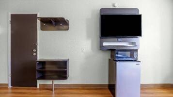 A room with a closed door, a small cabinet, a microwave, and a refrigerator.