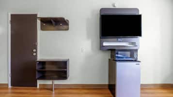A room with a closed door, a small cabinet, a microwave, and a refrigerator.