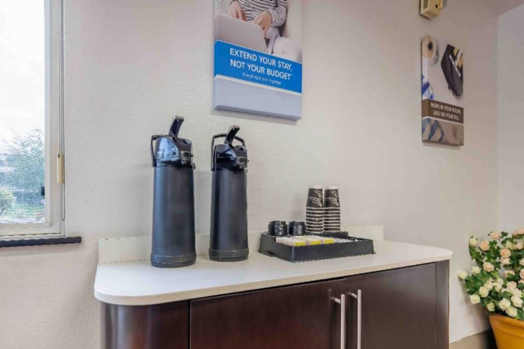 A reception area with two black water bottles on a counter, a poster on the wall, and a small stack of black and white cards.