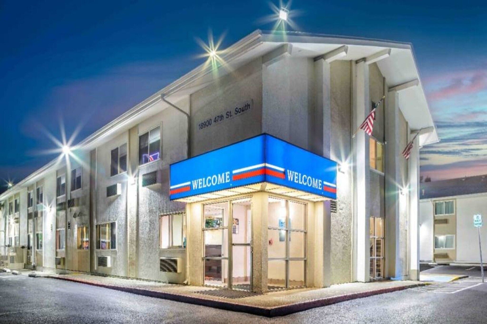 A hotel with a 'WELCOME' sign, a street view, and an American flag.
