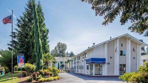 A motel with a '6 PARK A FLY' sign, a welcoming entrance, and a flag. - 2 Full Beds | Non-Smoking, Micfridge (Seattle)