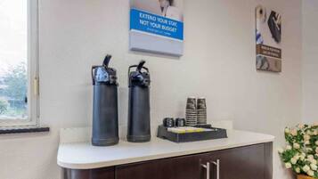 A reception area with two black water bottles on a counter, a poster on the wall, and a small stack of black and white cards.