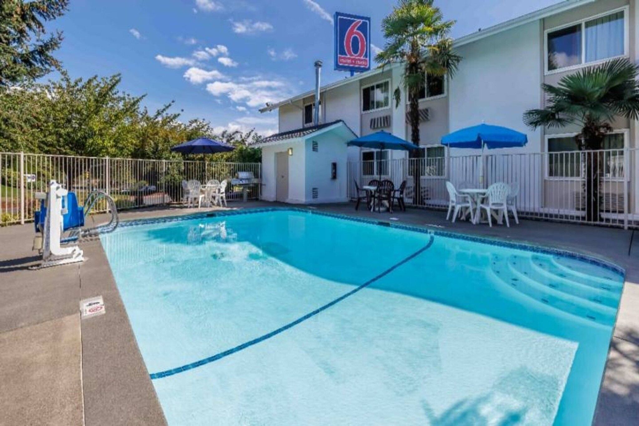 A hotel with a swimming pool, outdoor seating, and a sign indicating the number 6.