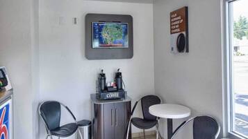 Een koffiehoekje met een koffieapparaat, twee stoelen en een tafel.