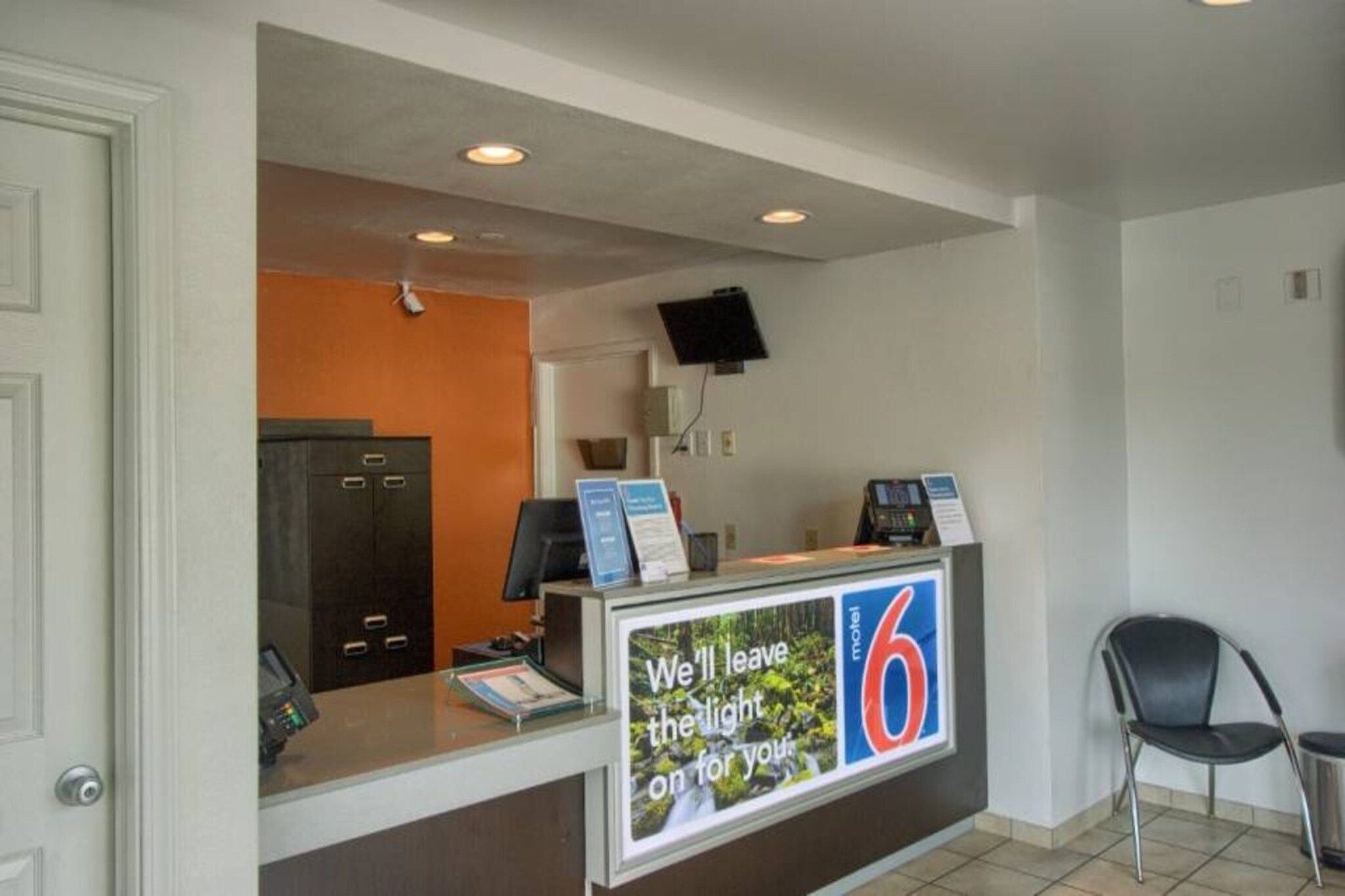 A reception desk with a sign indicating room number 6, a telephone, and a computer monitor.