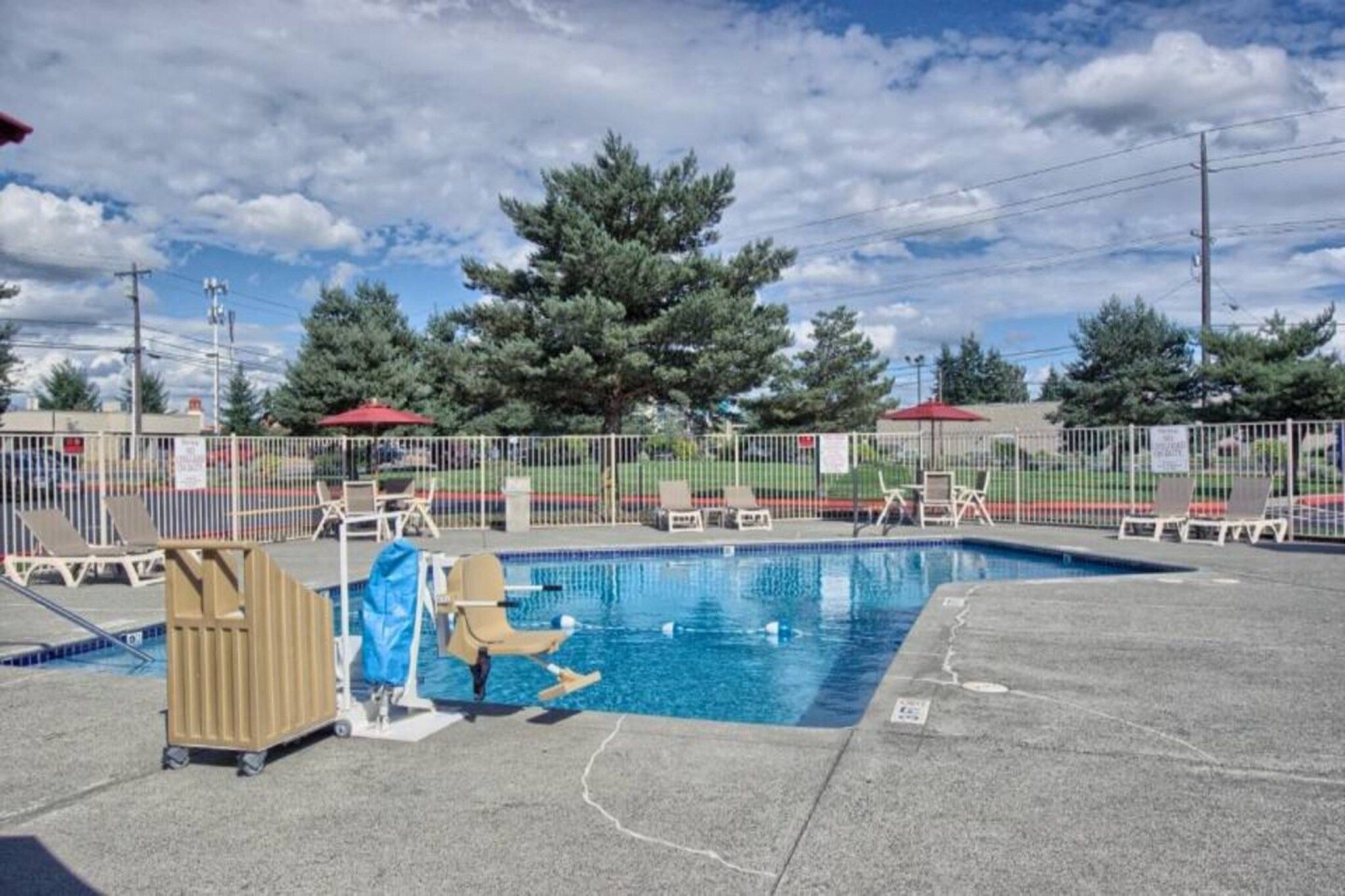 En swimmingpool med et afspærret område, liggestole og et overdækket siddeområde.