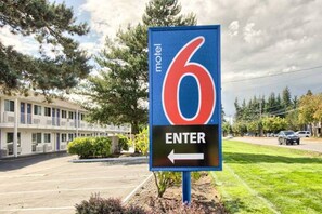 A motel sign with a number 6 and an arrow pointing left, indicating the entrance direction. - 1 Full Bed | ADA/RI Shower (Everett)