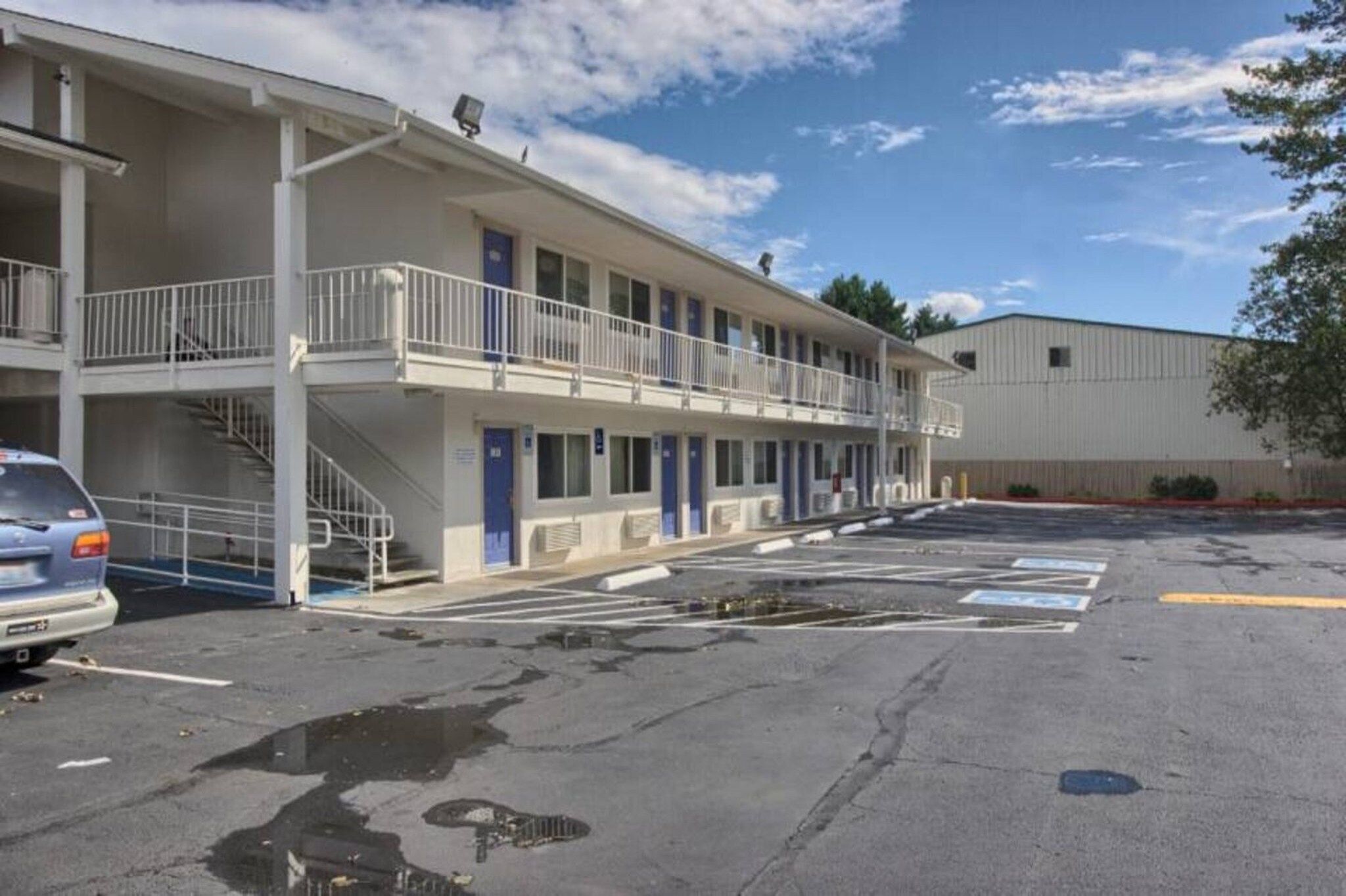Un motel con una struttura a due piani, un parcheggio e un edificio a un piano adiacente.