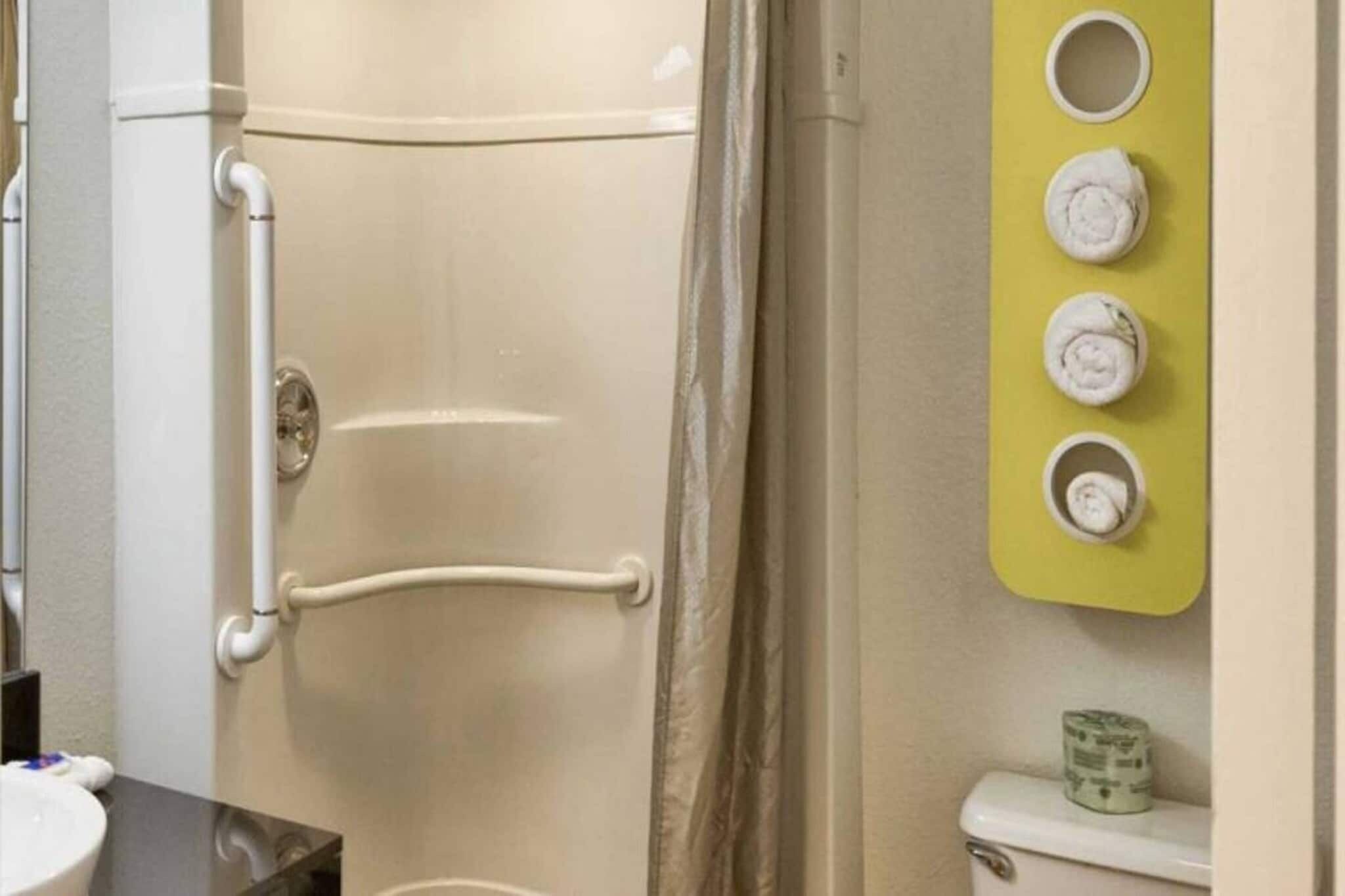 A bathroom with a white door, a towel rack with multiple towels, and a toilet.
