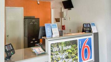 A reception desk with a sign reading 'We'll leave the light on for you' and a number '6' indicating the motel.