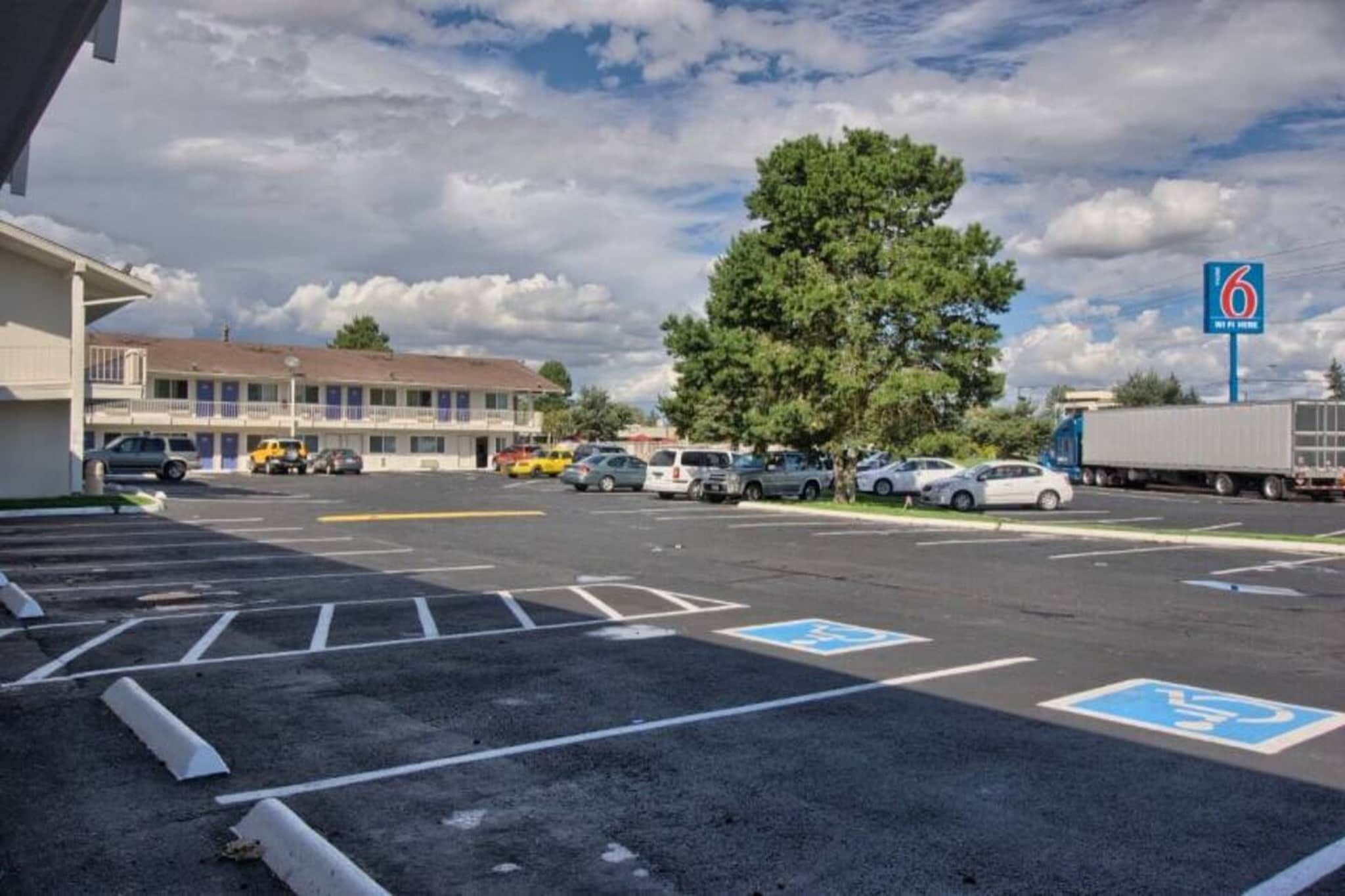 Un parcheggio con posti auto riservati ai disabili, un edificio motel e un camion.