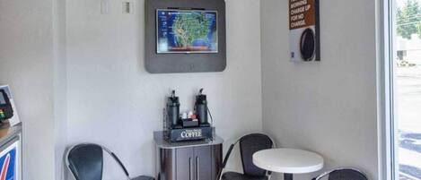 A small coffee station with a coffee machine, two chairs, and a table.