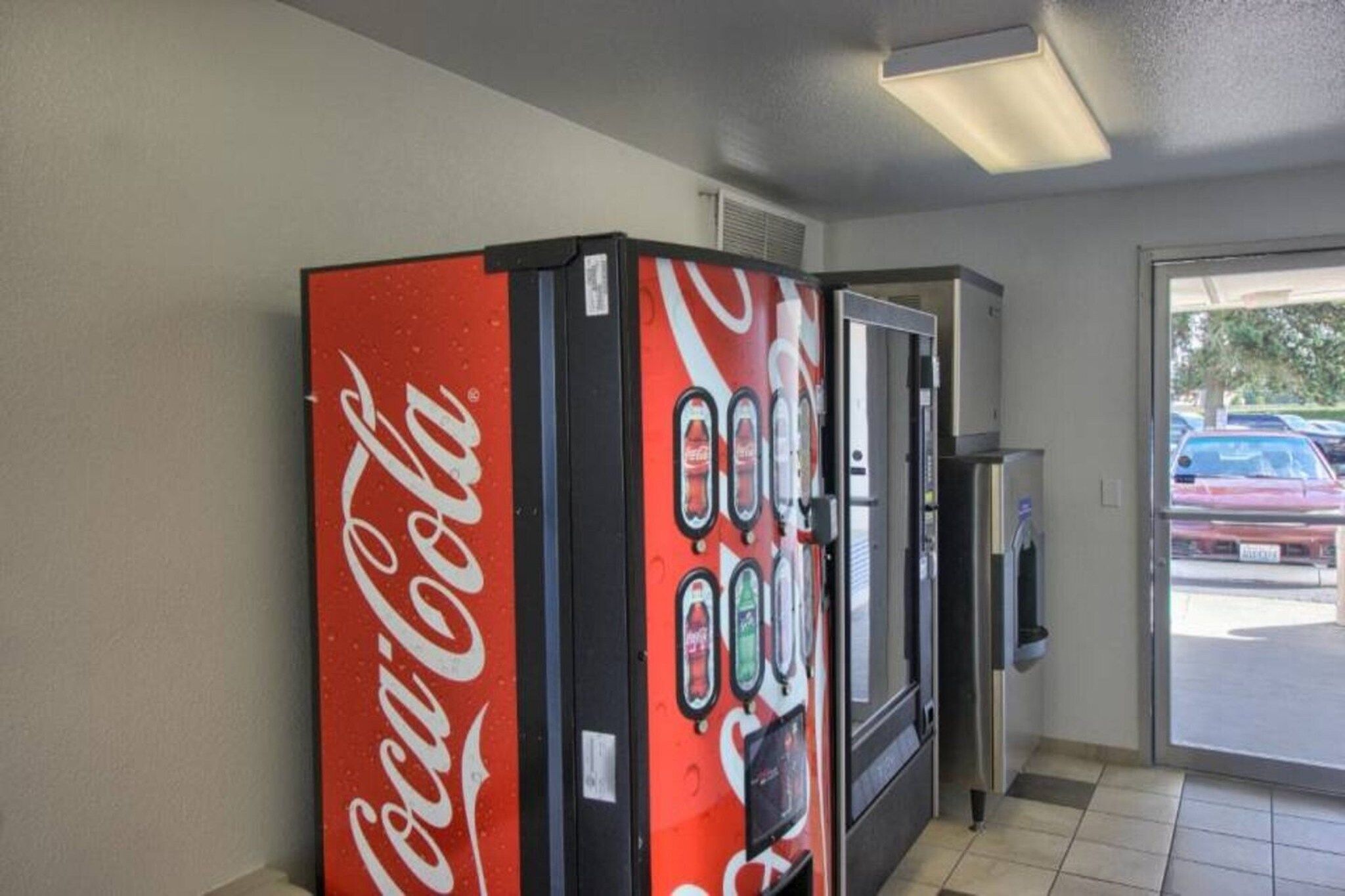 Máquina de vendas automática com logotipo da Coca-Cola, geladeira e micro-ondas.