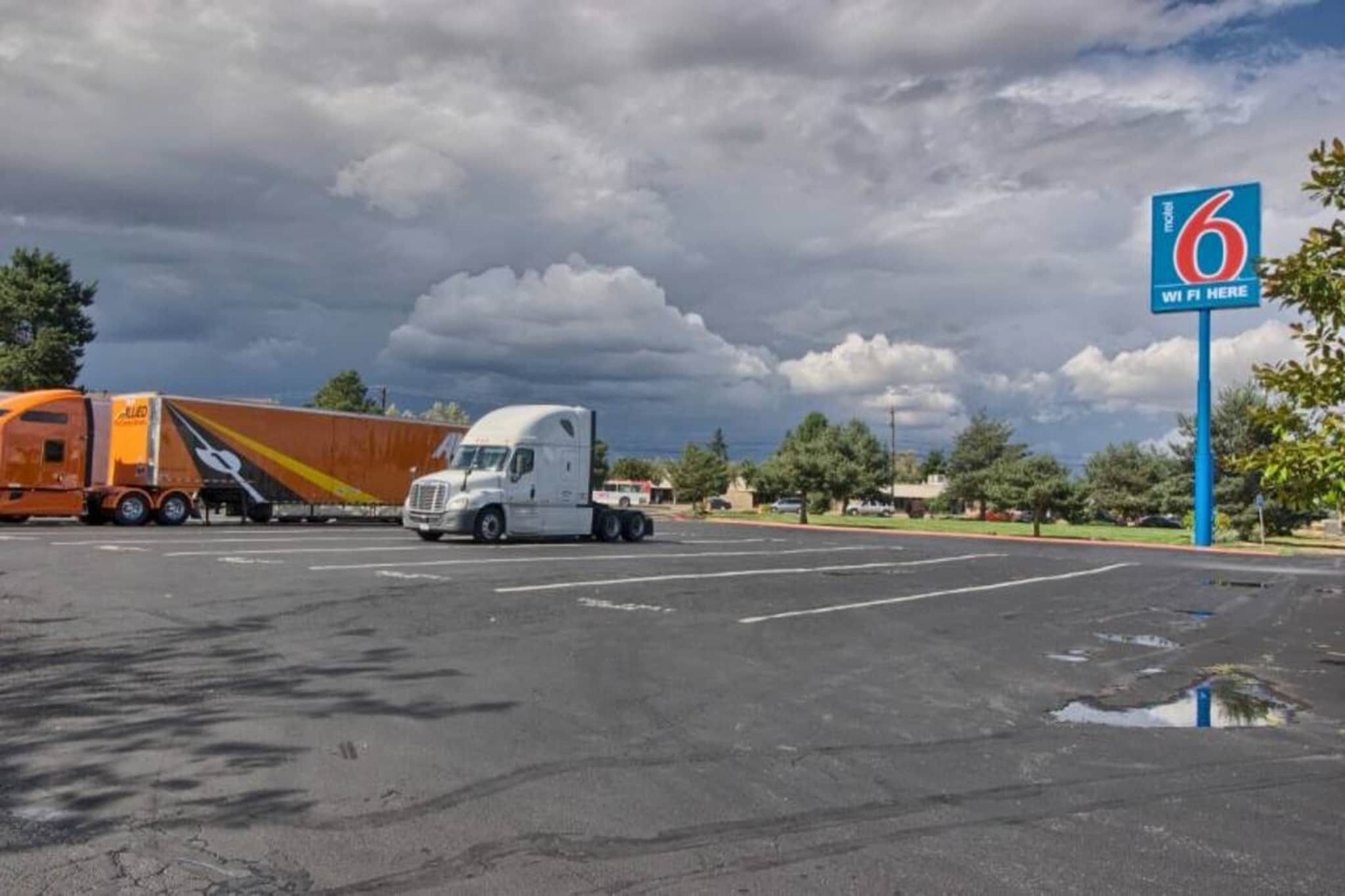 A parking lot with two trucks, one orange and one white, and a blue sign indicating WiFi availability.
