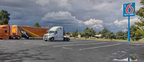 A parking lot with two trucks, one orange and one white, and a blue sign indicating WiFi availability.