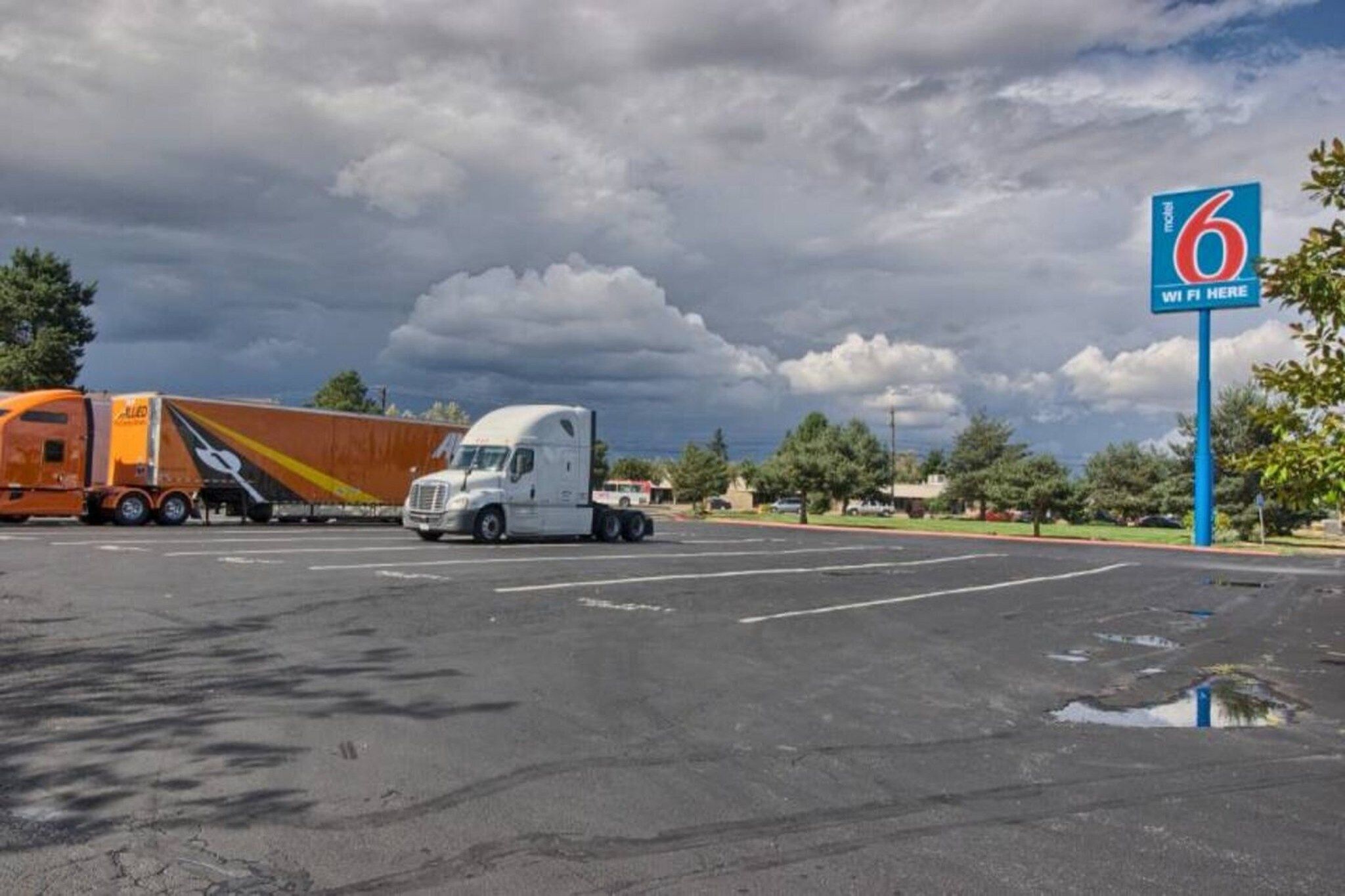 A parking lot with a large truck and a trailer, a clear sky, and a sign indicating WiFi availability.