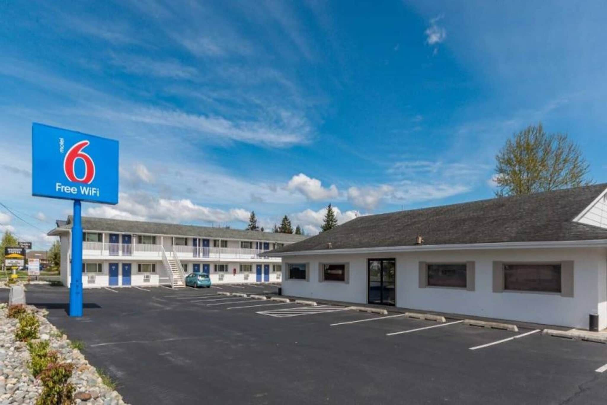 Um motel com placa indicando Wi-Fi gratuito, estacionamento e um edifício com telhado plano.