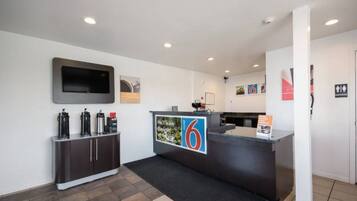 A reception area with a counter, a flat-screen TV, and a coffee station.