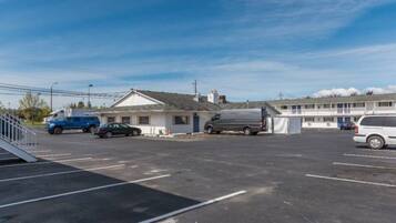 A parking lot with a motel and a small building, possibly a service station, with vehicles parked.