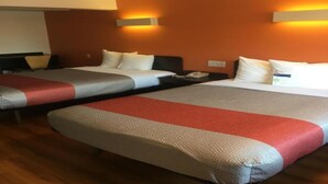 Een hotelkamer met twee bedden, elk voorzien van een rood-wit gestreepte dekbedovertrek, en twee wandlampen.