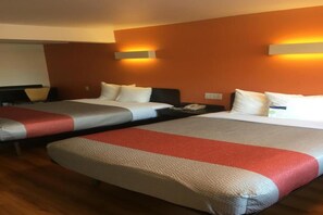 Une chambre d’hôtel avec deux lits, chacun recouvert d’une couvre-lit à rayures rouges et blanches, et deux lampes fixées au mur.
