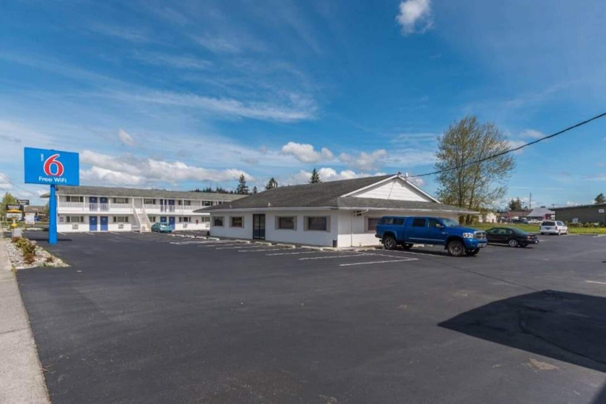 Um motel com placa indicando Wi-Fi gratuito, estacionamento e um edifício com telhado plano.