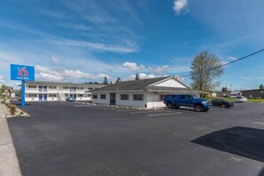 Um motel com placa indicando Wi-Fi gratuito, estacionamento e um edifício com telhado plano.