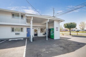 Um motel com entrada coberta, porta azul e máquina de vendas verde.