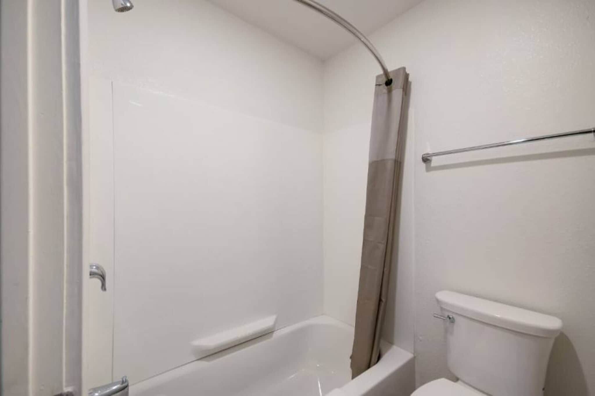 A bathroom with a bathtub, toilet, and shower curtain.