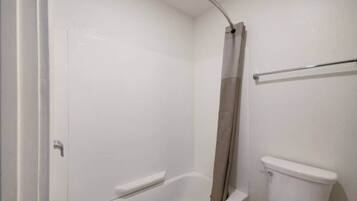 A bathroom with a bathtub, toilet, and shower curtain.
